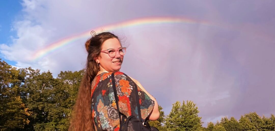 Paige smiling under a rainbow.